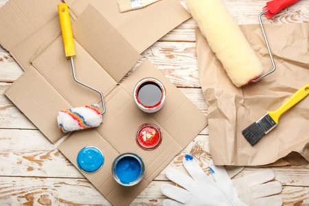Cans of paints, rollers, brush and gloves on light wooden backgroundの写真素材