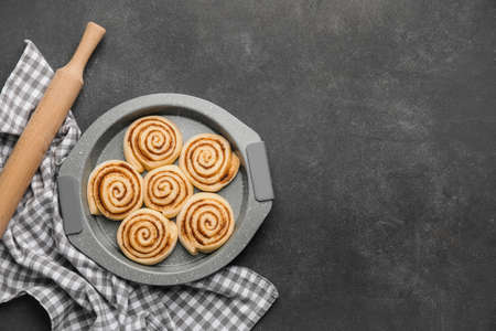 Baking dish with uncooked cinnamon rolls on dark background