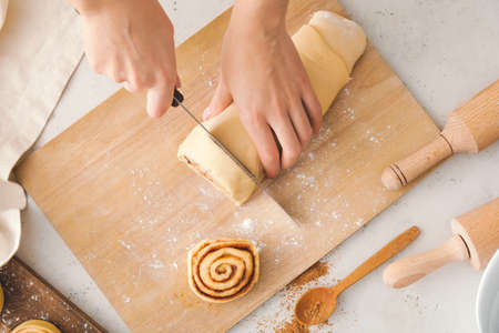 Woman preparing tasty cinnamon rolls in kitchenの写真素材