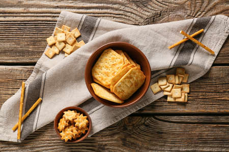 Bowls with tasty different crackers on wooden background
