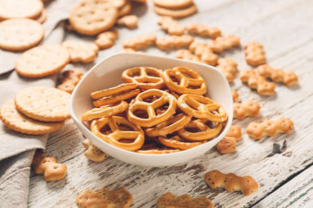 Bowl with tasty different crackers on light wooden backgroundの写真素材