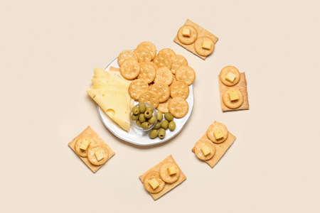 Plate with tasty crackers, cheese and olives on color backgroundの写真素材