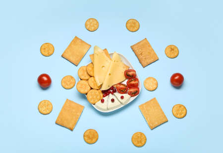 Plate with tasty crackers and snacks on color backgroundの写真素材