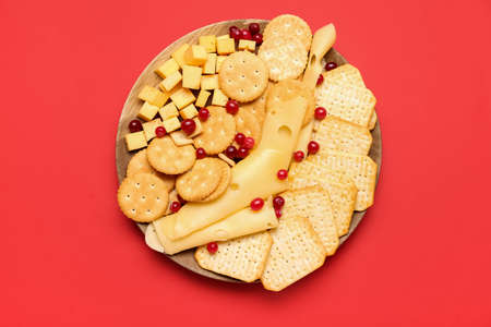 Plate with tasty crackers, cheese and cranberries on color backgroundの写真素材
