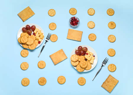 Plates with tasty crackers and snacks on color backgroundの写真素材