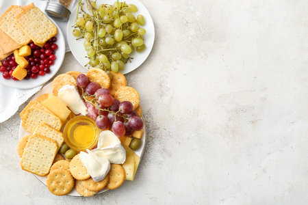 Plate with tasty crackers with cheese and snacks on light backgroundの写真素材