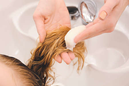 Female hairdresser washing hair of client in beauty salonの写真素材