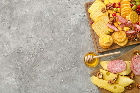 Board with tasty crackers with cheese and snacks on gray backgroundの写真素材