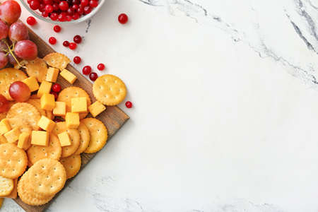 Board with tasty crackers with cheese and snacks on light backgroundの写真素材