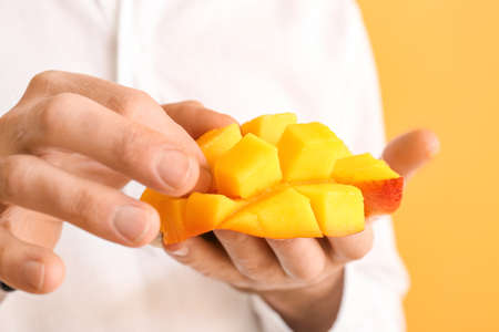 Man with cut mango on color background, closeupの写真素材