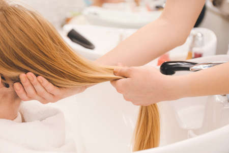 Female hairdresser washing hair of client in beauty salonの写真素材