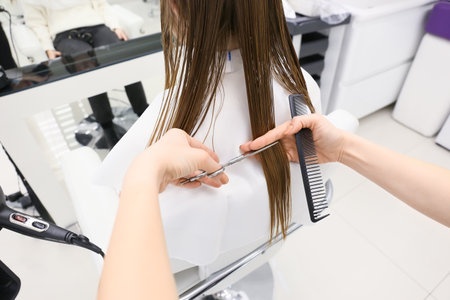 Female hairdresser cutting hair of client in beauty salon, closeupの写真素材