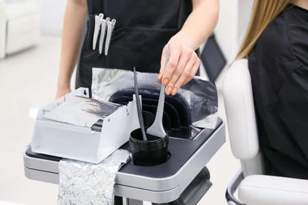 Professional hairdresser with brushes and coloring foil in beauty salonの写真素材