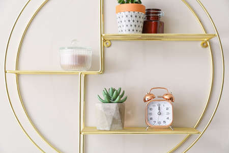Shelf with alarm clock and decor hanging on light wallの写真素材
