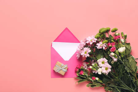 Beautiful flowers with gift and envelope on color backgroundの写真素材