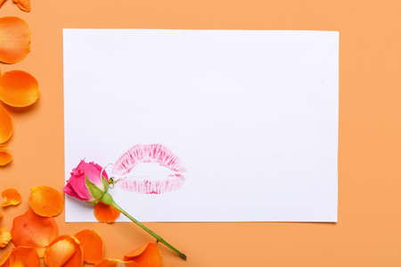 Empty greeting card with lips print and rose flowers on color backgroundの写真素材