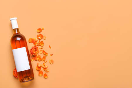 Bottle of wine with rose petals on color backgroundの写真素材