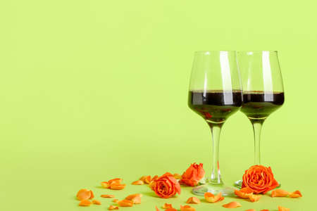Glasses of wine with rose flowers on color backgroundの写真素材