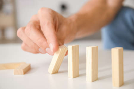 Man with wooden blocks at home, closeup. Bankruptcy conceptの写真素材