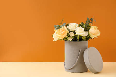 Gift box with beautiful flowers on table against color backgroundの写真素材