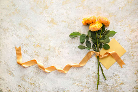 Bouquet of beautiful flowers and blank card on light backgroundの写真素材