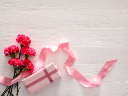 Bouquet of beautiful flowers and gift on white wooden backgroundの写真素材