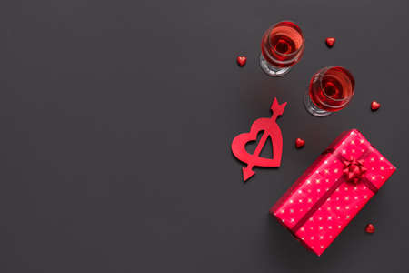 Glasses of wine and gift for Valentine's Day on dark backgroundの写真素材