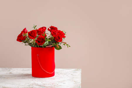 Gift box with beautiful flowers on table against color backgroundの写真素材
