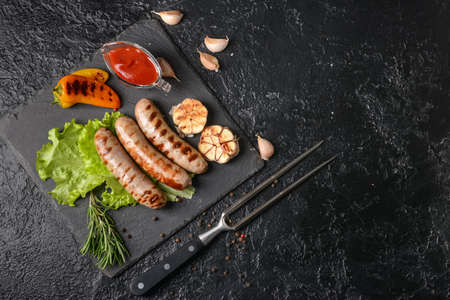 Slate plate with delicious grilled sausages on dark backgroundの写真素材