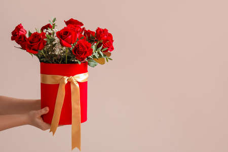 Hands with beautiful flowers on color background