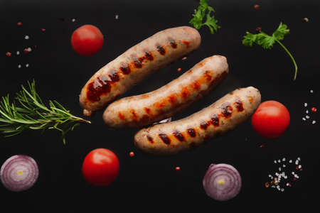 Delicious grilled sausages and vegetables on dark backgroundの写真素材