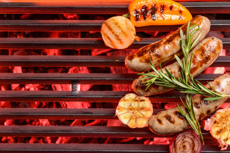 Delicious sausages and vegetables cooking on grillの写真素材