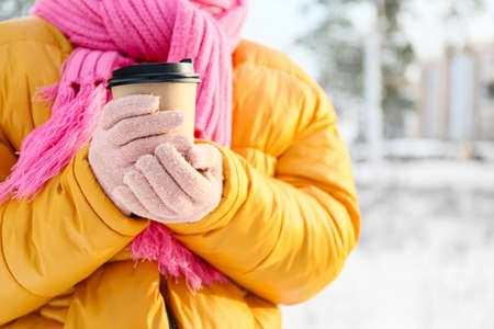 Young woman with cup of hot tea on snowy day, closeupの写真素材