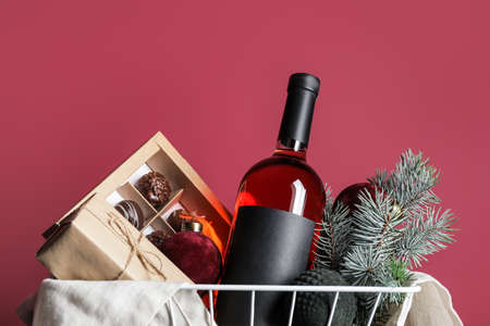 Gift basket with products and Christmas decor on color backgroundの写真素材