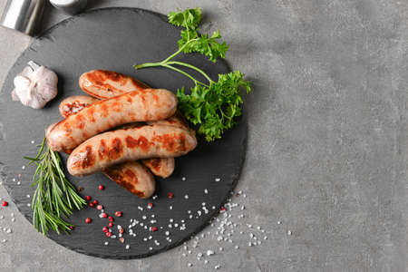 Slate plate with delicious grilled sausages on gray backgroundの写真素材