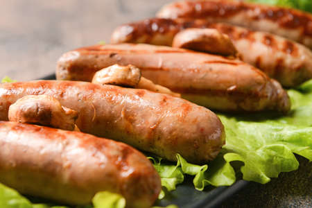 Plate with delicious grilled sausages on grunge background, closeupの写真素材