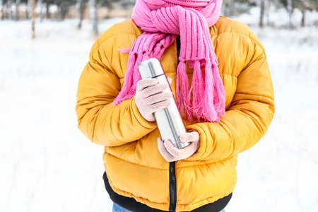 Young woman with thermos on snowy day, closeupの写真素材