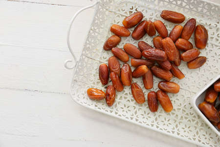 Tray with sweet dried dates on light wooden background