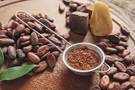 Cocoa beans, powder and butter on wooden board, closeupの写真素材