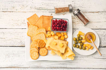 Platter with crunchy crackers, cranberry and cheese on white wooden backgroundの写真素材