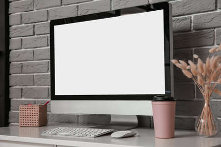 Modern computer on table near brick wallの写真素材