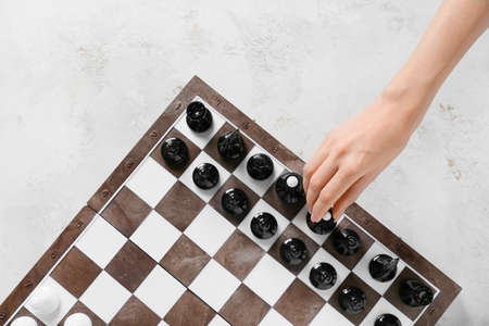 Woman playing chess on light background