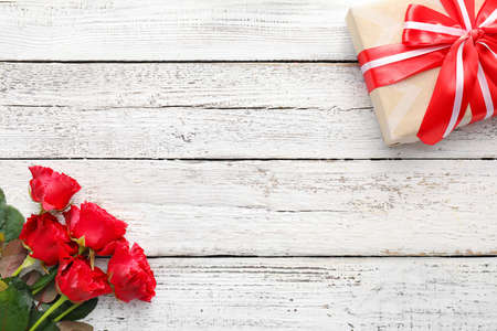 Bouquet of beautiful flowers and gift on white wooden backgroundの写真素材