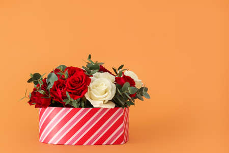 Gift box with beautiful flowers on color backgroundの写真素材