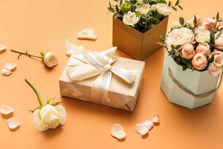Gift box and beautiful flowers on color backgroundの写真素材