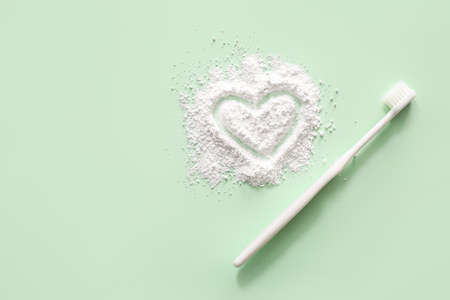 Heart made of tooth powder and brush on color backgroundの写真素材
