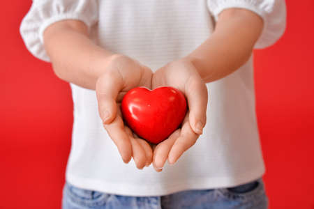Young woman with red heart on color background, closeupの写真素材