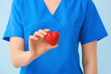 Doctor with red heart on color background, closeupの写真素材