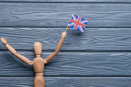 Human figurine with national flag of the United Kingdom on wooden backgroundの写真素材