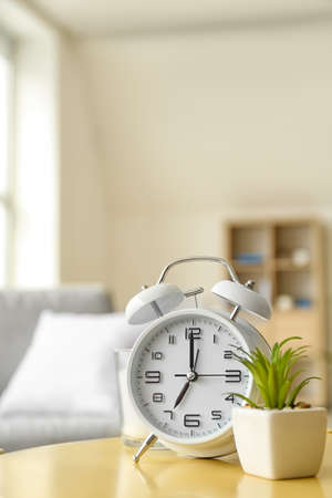 Alarm clock and houseplant on table in roomの写真素材
